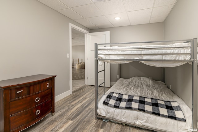 bedroom with baseboards, a paneled ceiling, and wood finished floors