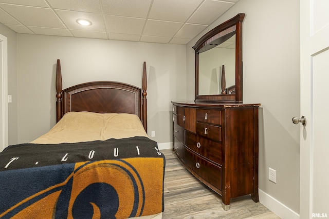 bedroom with a drop ceiling, baseboards, and light wood finished floors