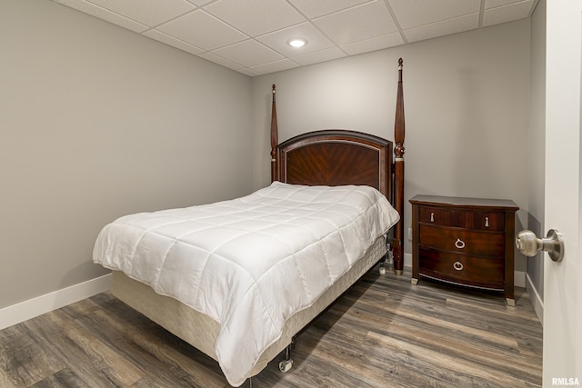 bedroom featuring a paneled ceiling, baseboards, and wood finished floors