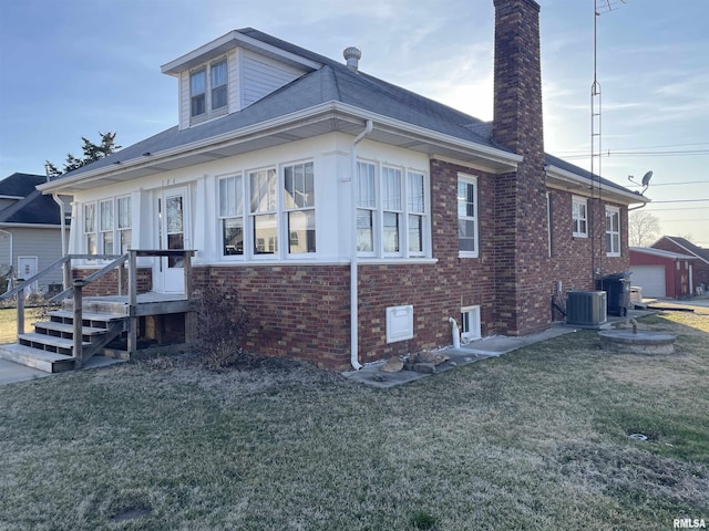 view of home's exterior with a yard, brick siding, and cooling unit