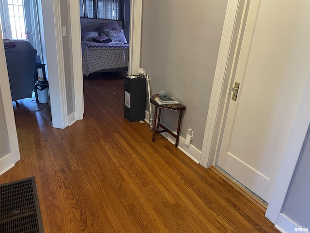 hallway featuring visible vents, baseboards, and wood finished floors