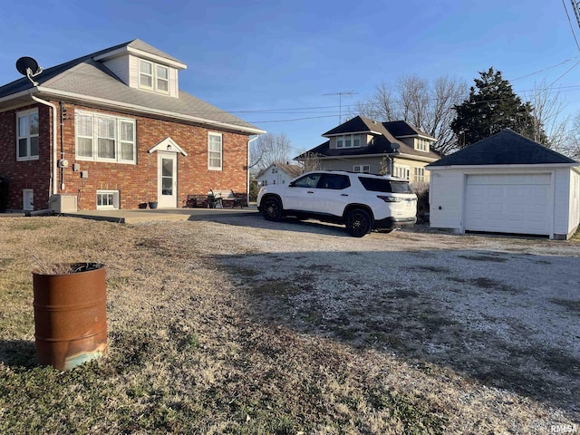 view of property exterior featuring a garage, brick siding, an outdoor structure, and driveway