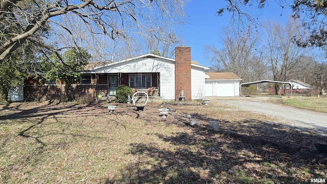 view of front of home featuring an outdoor structure, a garage, driveway, and a chimney