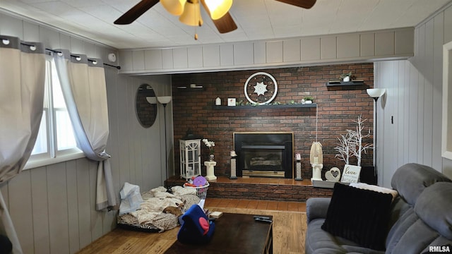 living room featuring a fireplace, wood finished floors, and a ceiling fan