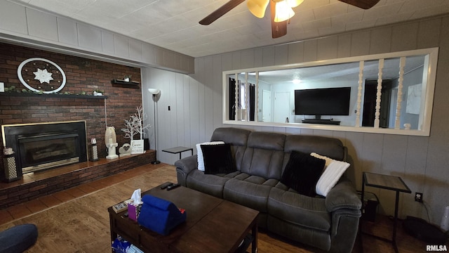 living area with a brick fireplace, ceiling fan, and wood finished floors