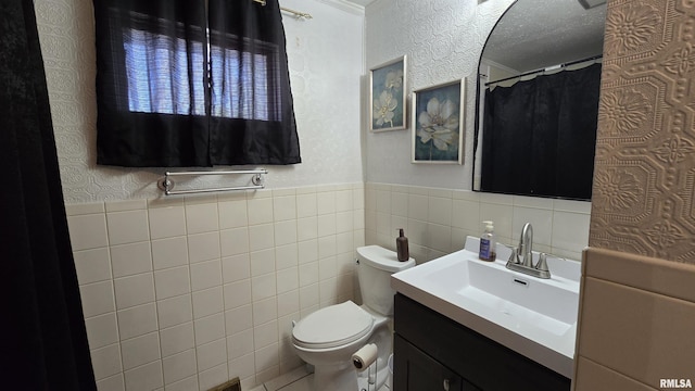 full bath with vanity, tile walls, toilet, and a textured wall