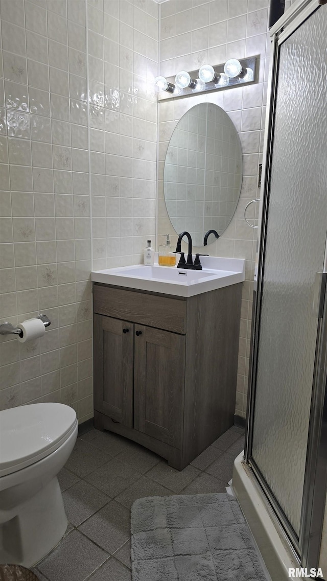 bathroom with tile patterned flooring, a shower stall, toilet, vanity, and tile walls