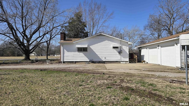 rear view of house with an outbuilding, a garage, a chimney, and crawl space