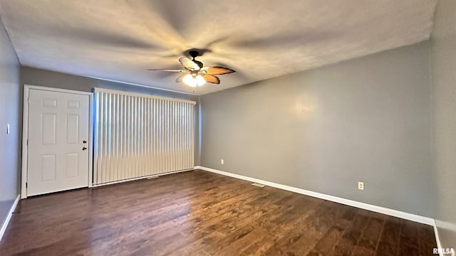 unfurnished room with dark wood-style floors, baseboards, and ceiling fan