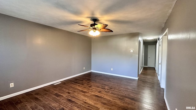 empty room with baseboards and dark wood-type flooring