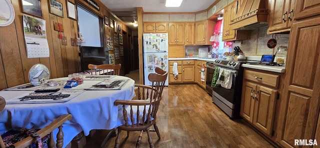 kitchen featuring wood finished floors, custom exhaust hood, freestanding refrigerator, light countertops, and electric stove