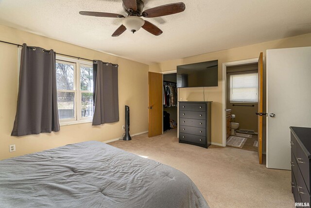 bedroom featuring ensuite bath, a closet, baseboards, light colored carpet, and a spacious closet