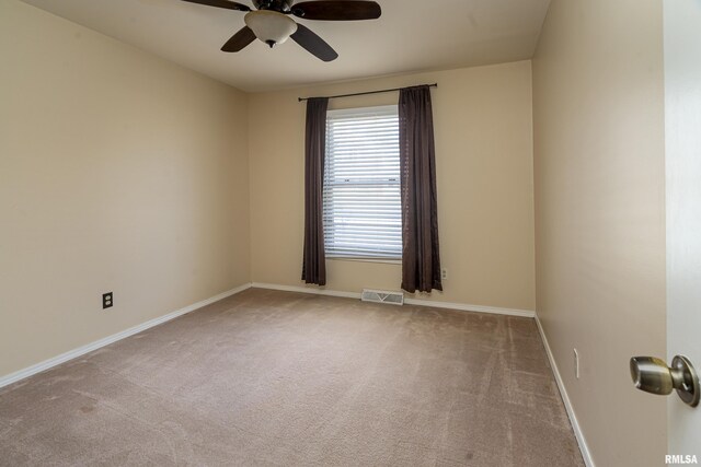 carpeted spare room with baseboards, visible vents, and ceiling fan