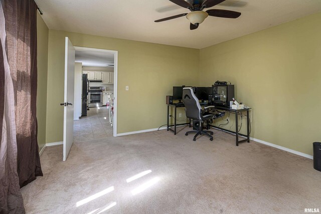 unfurnished office featuring a ceiling fan, light colored carpet, and baseboards