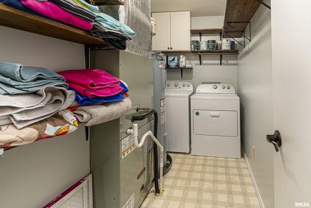 laundry area featuring cabinet space, light floors, and washing machine and clothes dryer