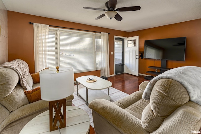 living area featuring baseboards, a ceiling fan, and wood finished floors