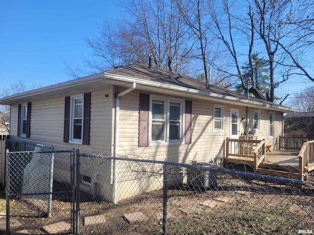 view of property exterior featuring a fenced front yard, a wooden deck, and a gate