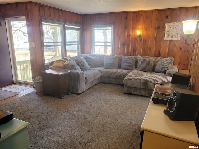 carpeted living room featuring wooden walls and a textured ceiling