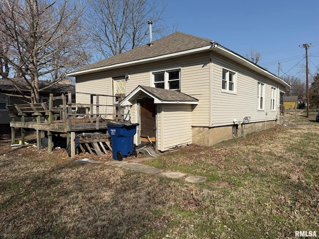 rear view of house featuring a lawn, a wooden deck, and a shingled roof