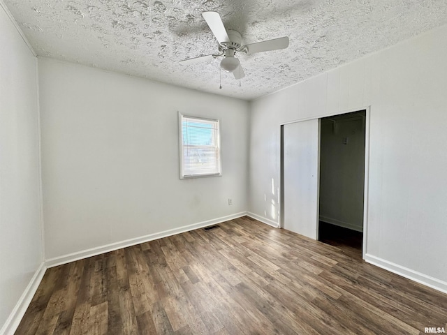 unfurnished bedroom with wood finished floors, baseboards, ceiling fan, a closet, and a textured ceiling