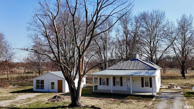 view of front of property with metal roof, covered porch, and dirt driveway