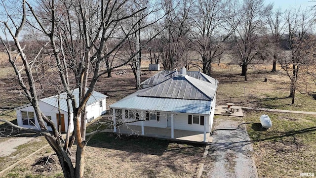 view of side of property featuring metal roof, a patio, and driveway