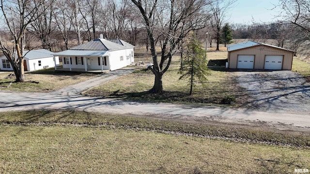 exterior space featuring an outbuilding, a front lawn, covered porch, metal roof, and a garage