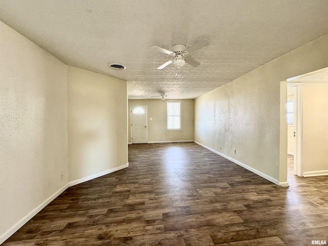 spare room with ceiling fan, visible vents, a textured ceiling, and dark wood finished floors