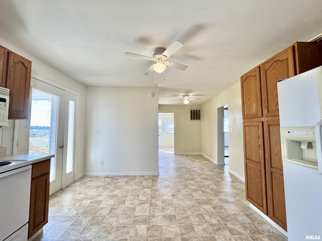 kitchen with baseboards, white appliances, a healthy amount of sunlight, and brown cabinetry