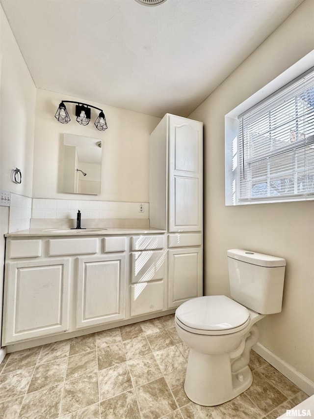 bathroom with toilet, vanity, and baseboards