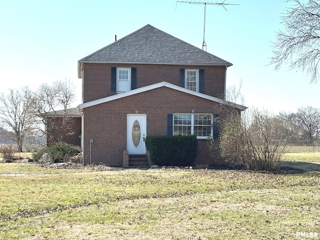 view of front of house with brick siding, a front yard, and roof with shingles