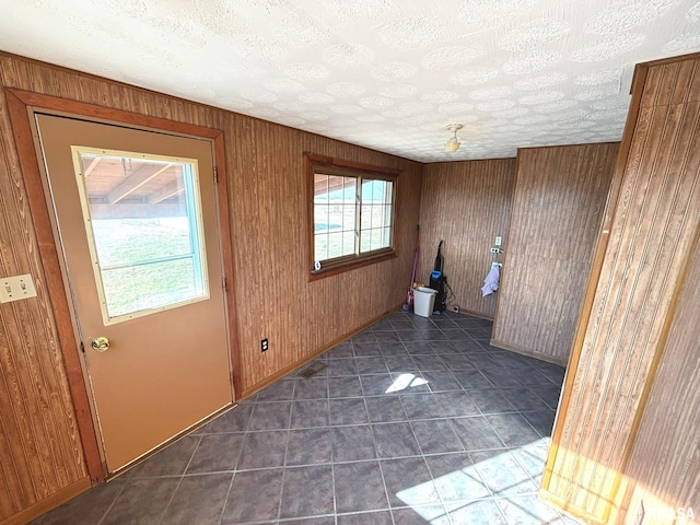 interior space with tile patterned flooring, wooden walls, visible vents, and a textured ceiling