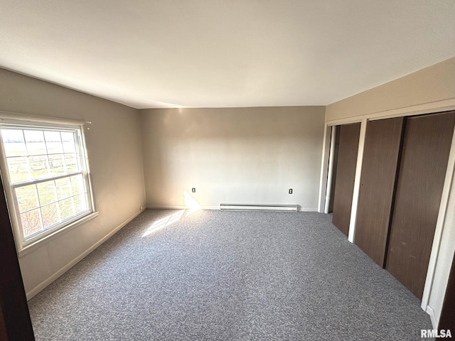 unfurnished bedroom with a baseboard heating unit, carpet floors, two closets, and baseboards