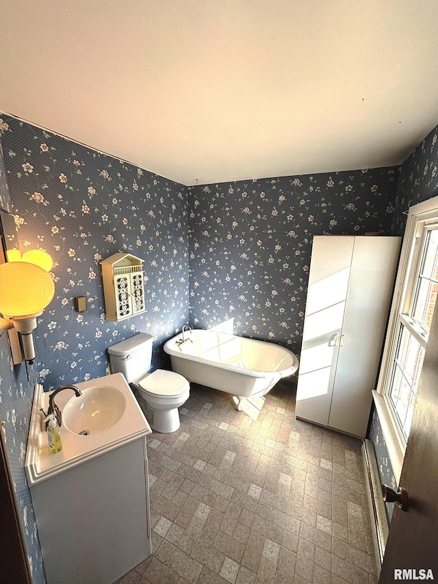 full bath with vanity, a baseboard radiator, wallpapered walls, a soaking tub, and toilet