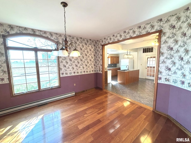 spare room featuring visible vents, wallpapered walls, wood-type flooring, and a baseboard radiator