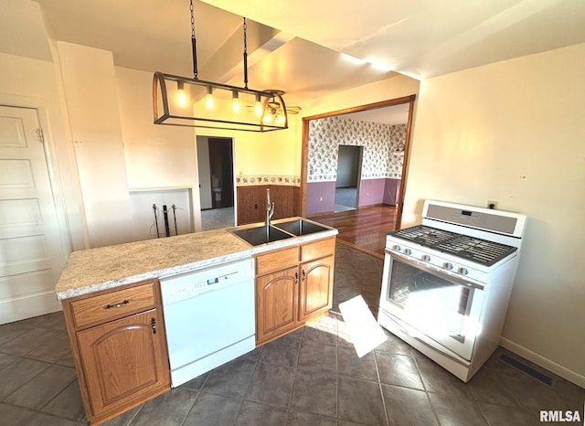 kitchen featuring white appliances, visible vents, wallpapered walls, a sink, and decorative light fixtures