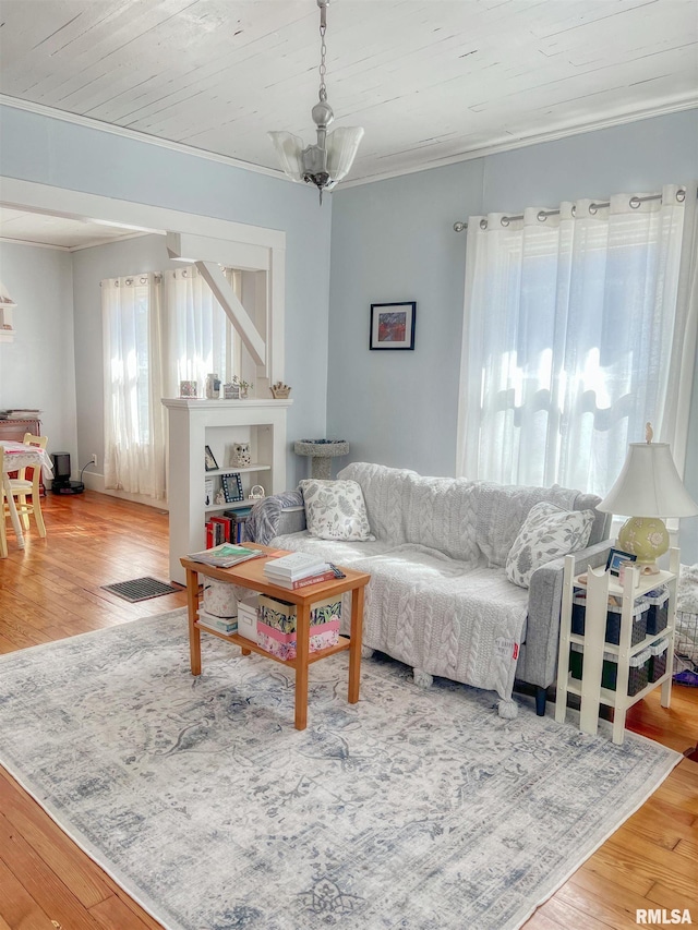 living area with wooden ceiling, an inviting chandelier, wood finished floors, and crown molding