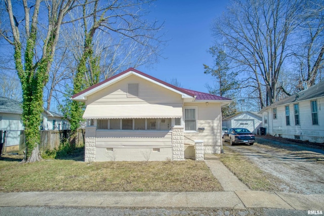 bungalow-style home with fence, metal roof, an outdoor structure, a front yard, and crawl space