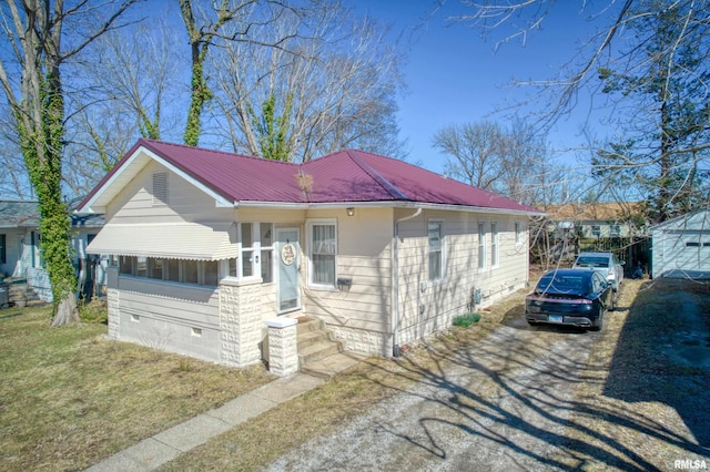 view of front facade featuring crawl space, metal roof, driveway, and a front lawn