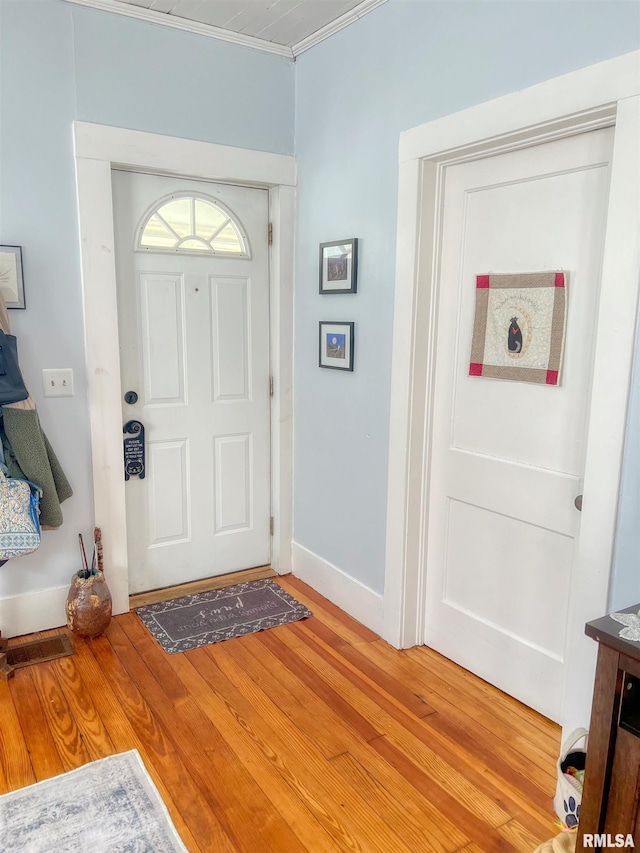 foyer entrance featuring baseboards, light wood-style flooring, and crown molding