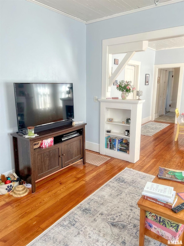 living room with crown molding, baseboards, and light wood-type flooring