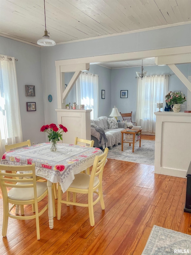 dining area with light wood-type flooring, wood ceiling, a chandelier, and crown molding