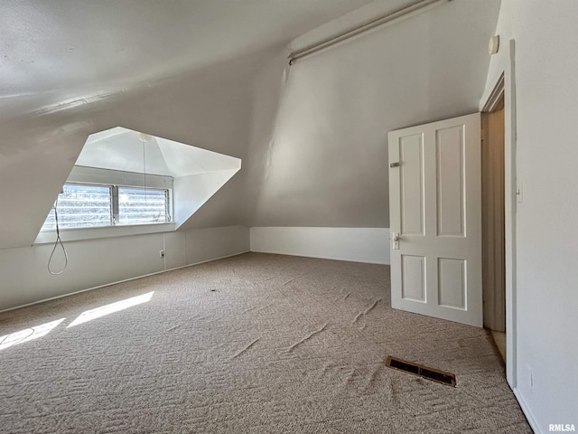 additional living space with lofted ceiling, visible vents, and carpet floors