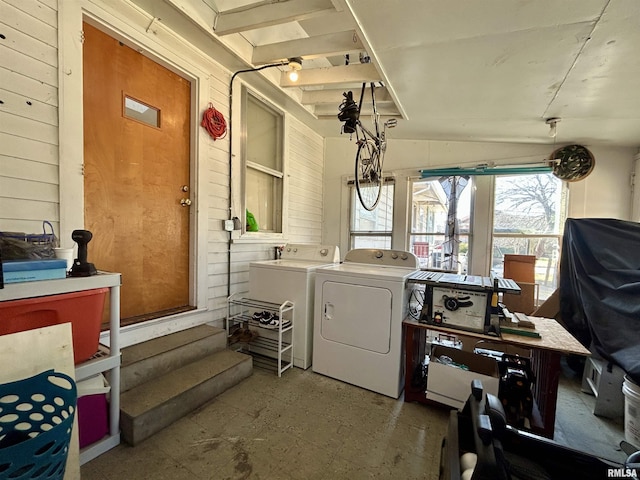 clothes washing area with washer and clothes dryer, laundry area, and wood walls