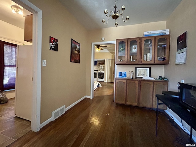 hallway featuring visible vents, dark wood-type flooring, an inviting chandelier, baseboards, and washer / dryer