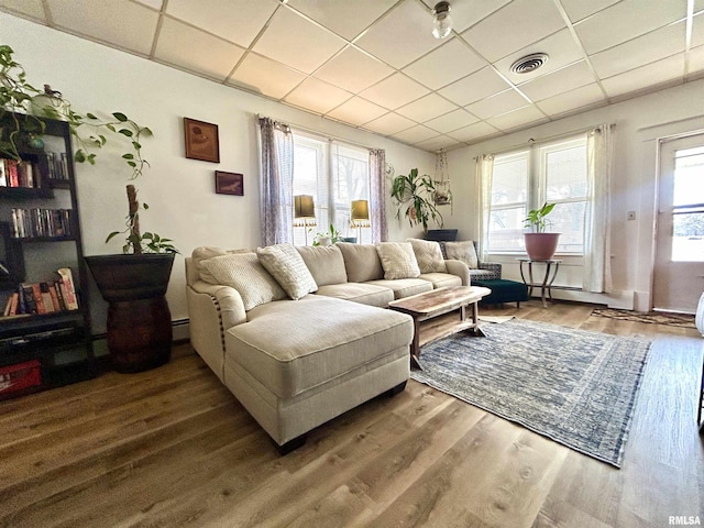 living room with a wealth of natural light, visible vents, and a drop ceiling