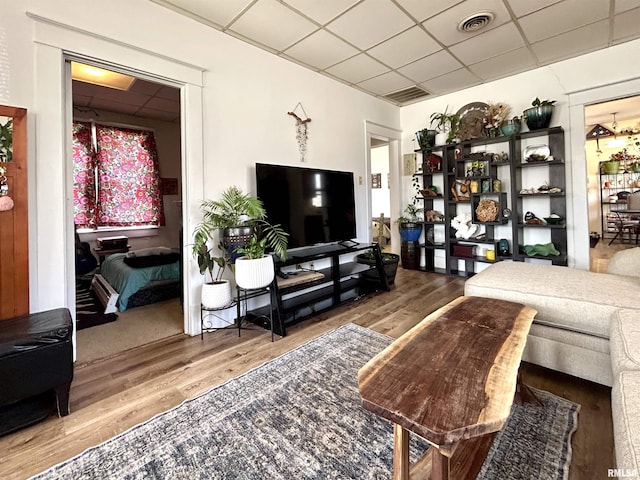 living area with visible vents, a paneled ceiling, and wood finished floors