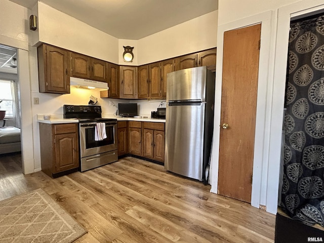 kitchen with light wood-style flooring, light countertops, dark brown cabinetry, under cabinet range hood, and appliances with stainless steel finishes