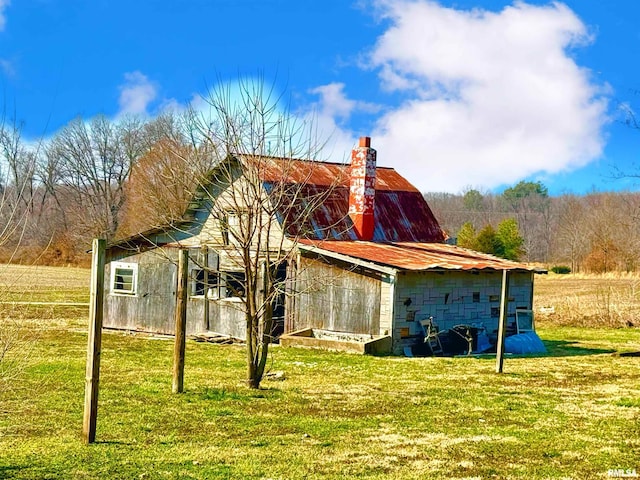 exterior space featuring concrete block siding, a yard, a chimney, an outdoor structure, and a barn