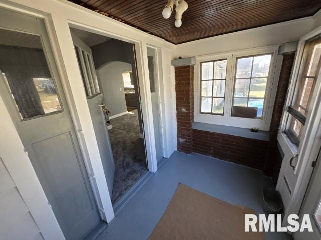 unfurnished sunroom featuring arched walkways and wooden ceiling